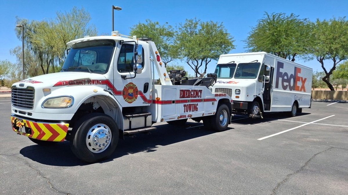Emergency Towing medium-duty wrecker towing a FedEx Ground delivery box truck in the East Valley